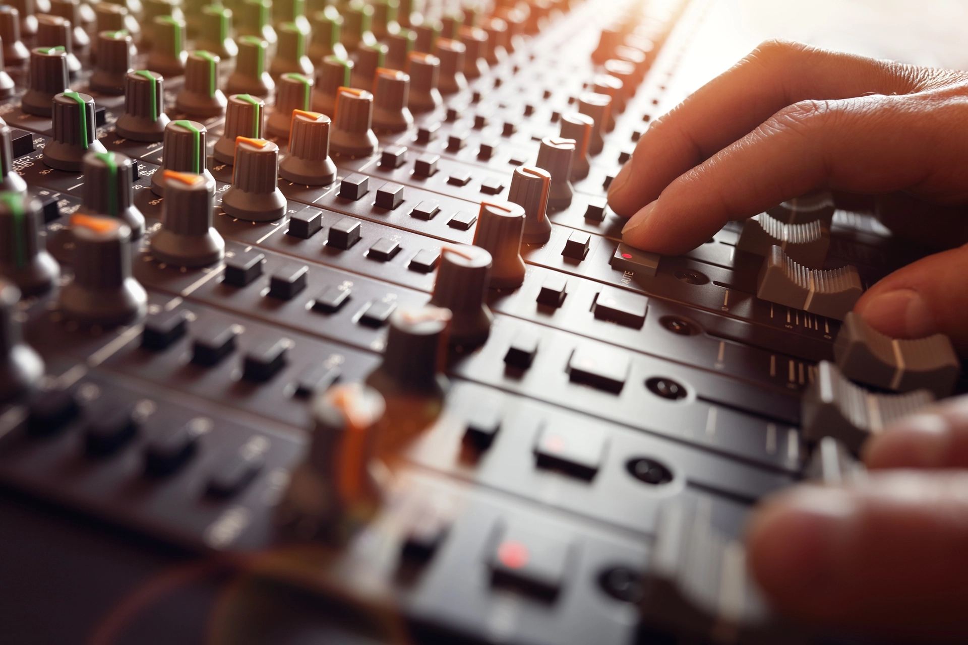 An image of a sound board with someone adjusting the dials